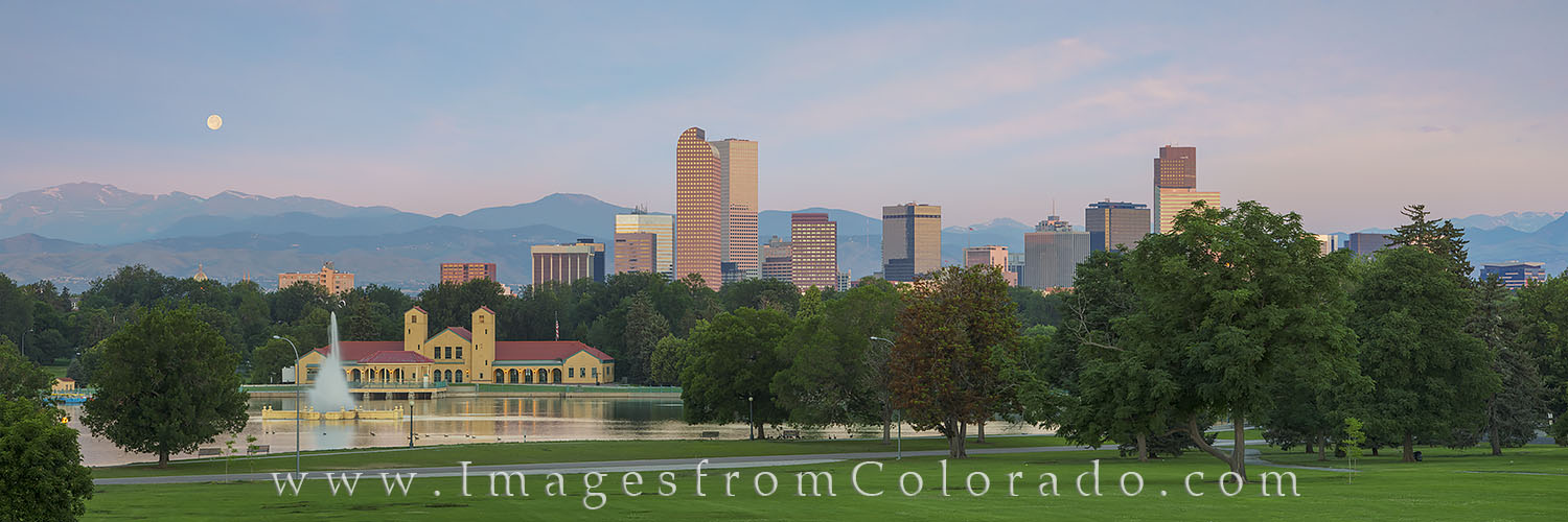 The full moon sets over the Rocky Mountains and the downtown Denver skyline just before sunrise on a July morning. This panorama...