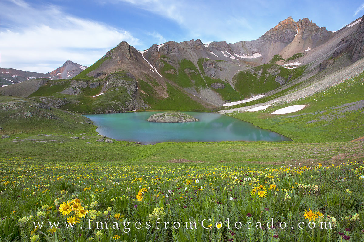 Golden Colorado wildflowers fill the grassy slopes near Island Lake. Nested in a cirque and surrounded by the peaks of several...