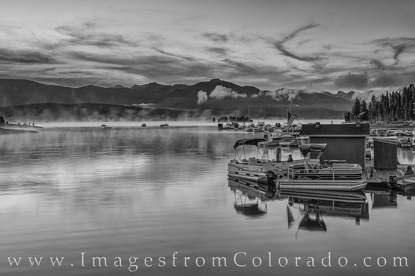 Along the shores of Lake Granby near Grand Lake, Colorado, boats rest quietly on a cold summe morning in this black and white...