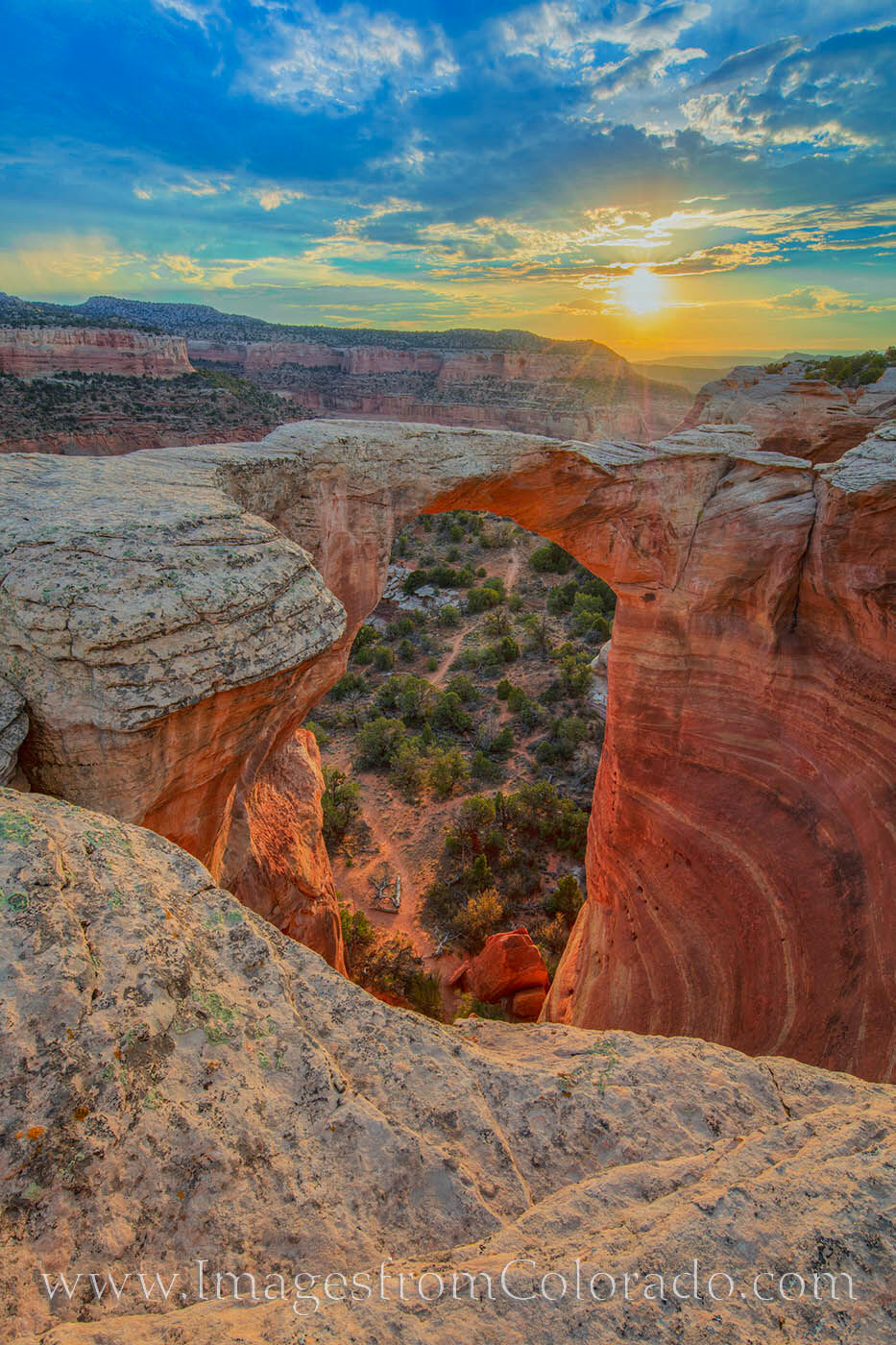 Sunset comes to Rattlesnake Canyon on a warm summer evening. Here, the iconic Centennial Arch, known by other names including...