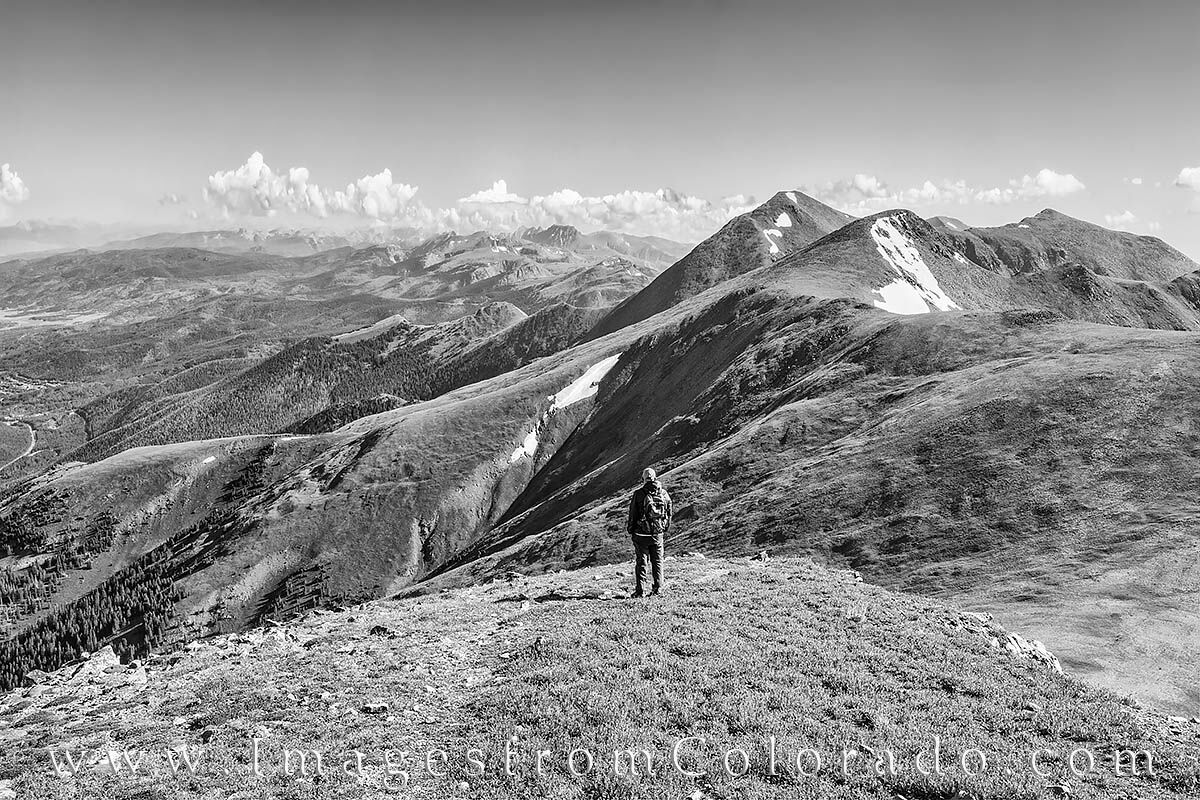 A hiker looks at Mount Eva and Parry Peak in the distance on a cool summer morning along the CDT Trail. This black and white...